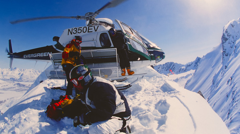 helicopter and skiers on snowy mountain