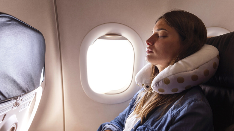 Woman sleeping with a travel pillow on flight