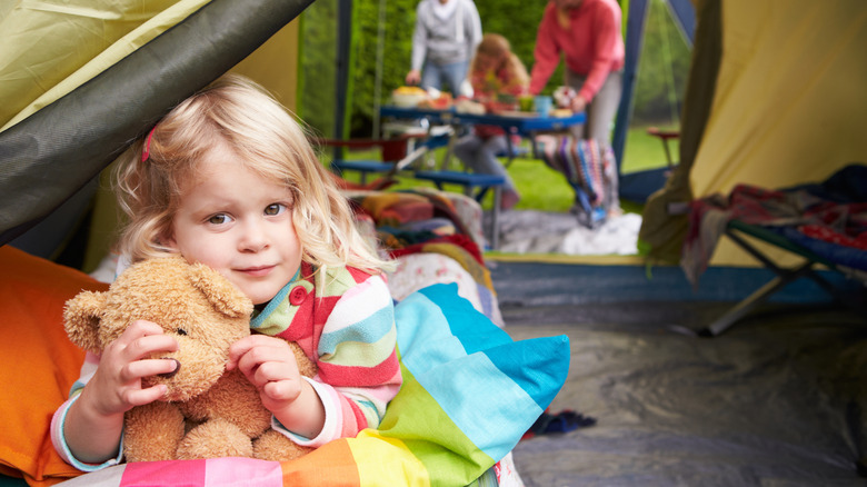 Child hugging teddy in tent