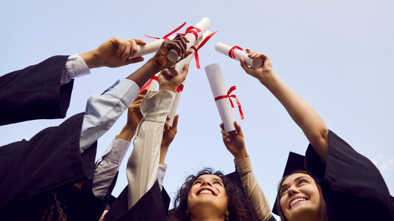 Happy graduates toast with their diplomas