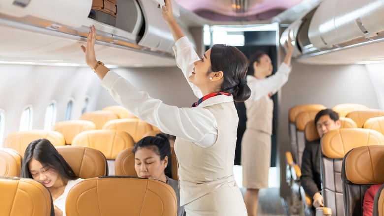 Flight attendants closing overhead bins