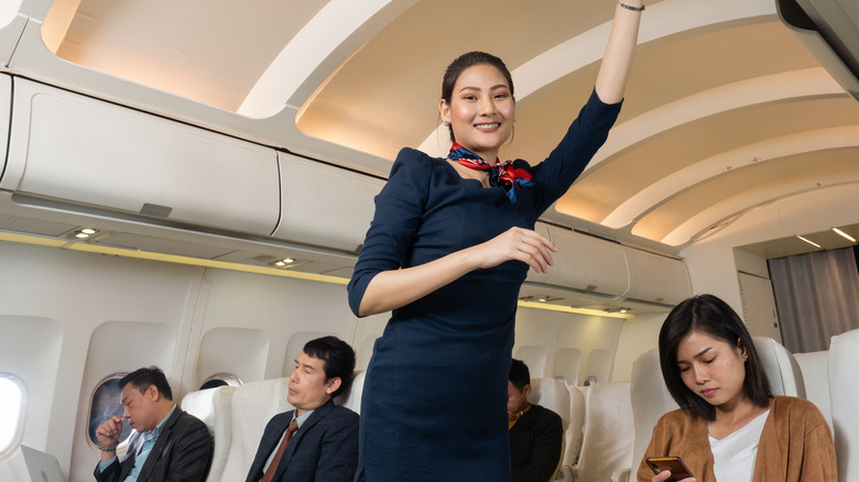 Tall flight attendant closing overhead bin