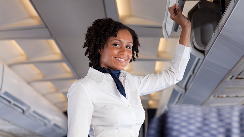 Flight attendant closing an overhead bin