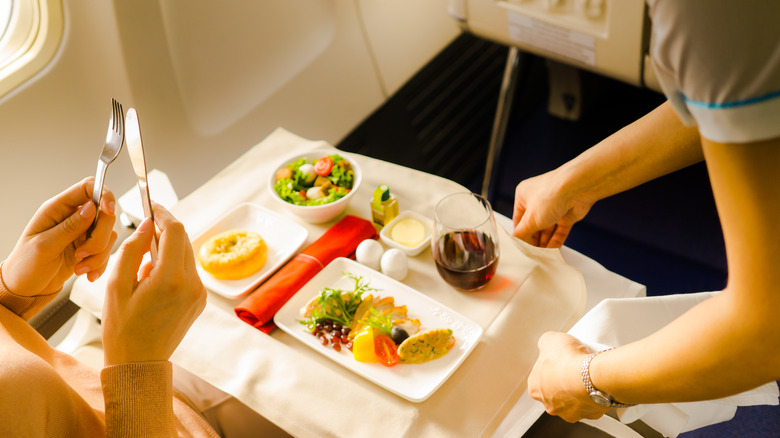 Flight attendant serving passenger a meal