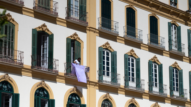 Woman hanging sheets to dry on a balcony