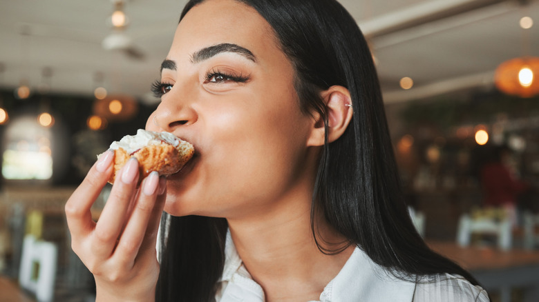 Smiling traveler biting into pastry