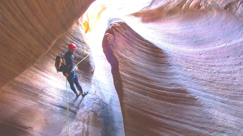 Canyoneer rappelling into slot canyon