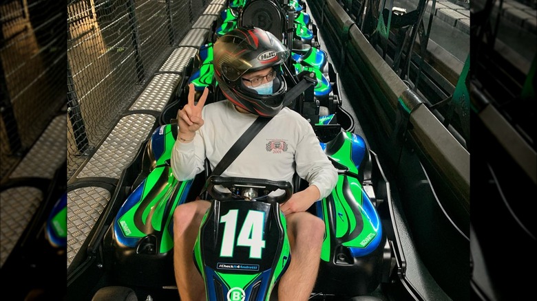 Man on a racing kart holding up a peace sign