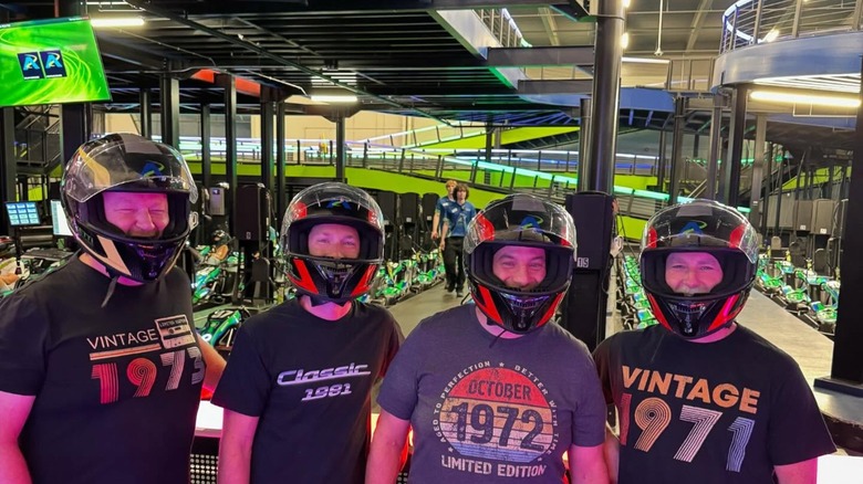 Group of men in race helmets by karting track