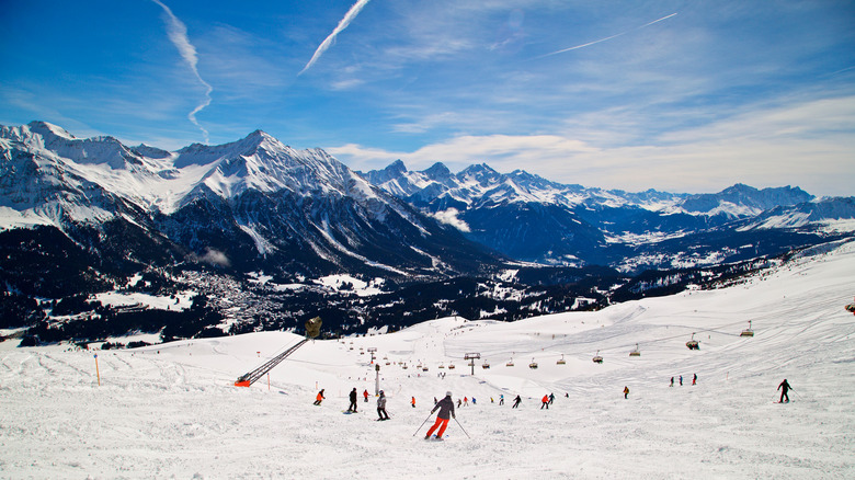 Skiers on slopes with Swiss Alps in the distance