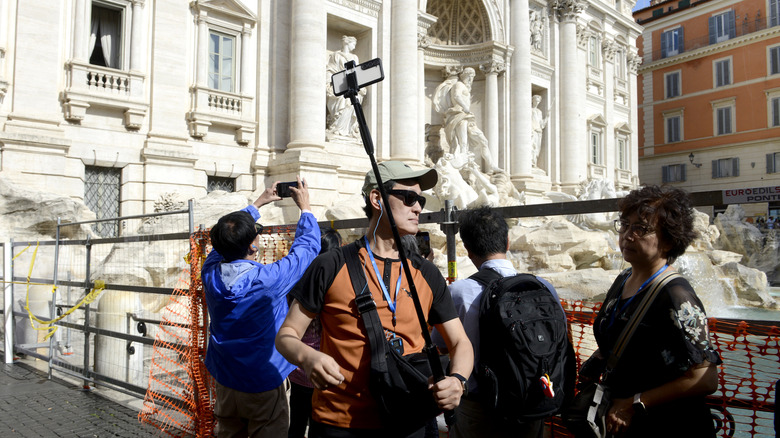 Tourists take pictures of the Trevi Fountain in Rome