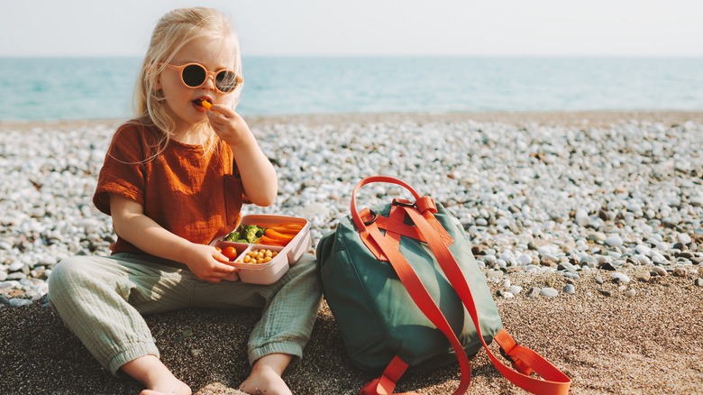 Child eating snacks on beach