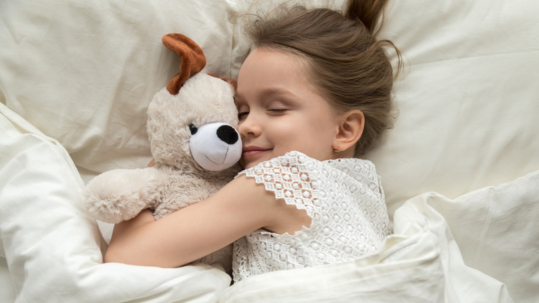 Girl cuddling toy in bed