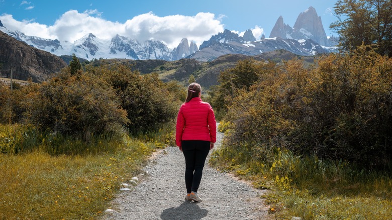 Traveler on gravel road facing Patagonia mountains