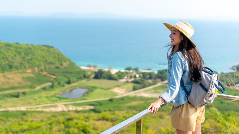 Asian woman with backpack on tropical island with mountain