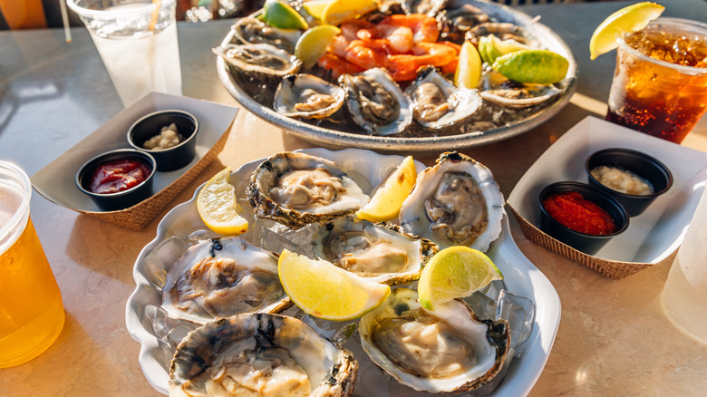 Plates of fresh oysters and shrimp with sauce and drinks.