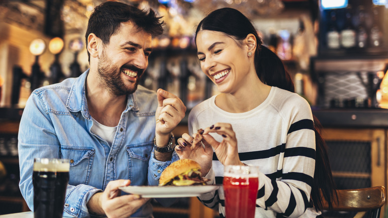 A couple eating and drinking beer.