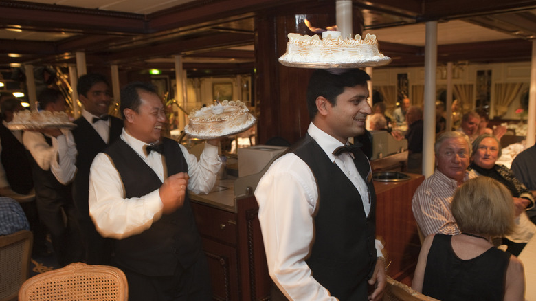 men serving cakes on cruise