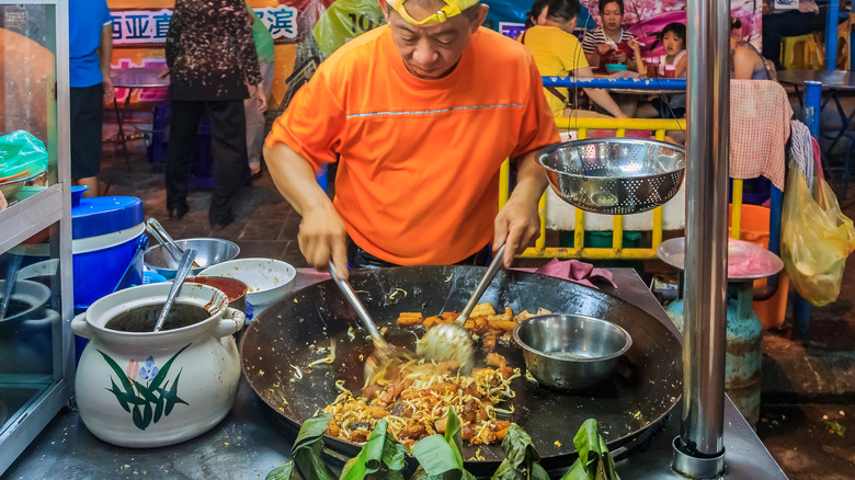 Man cooking noodles in wok