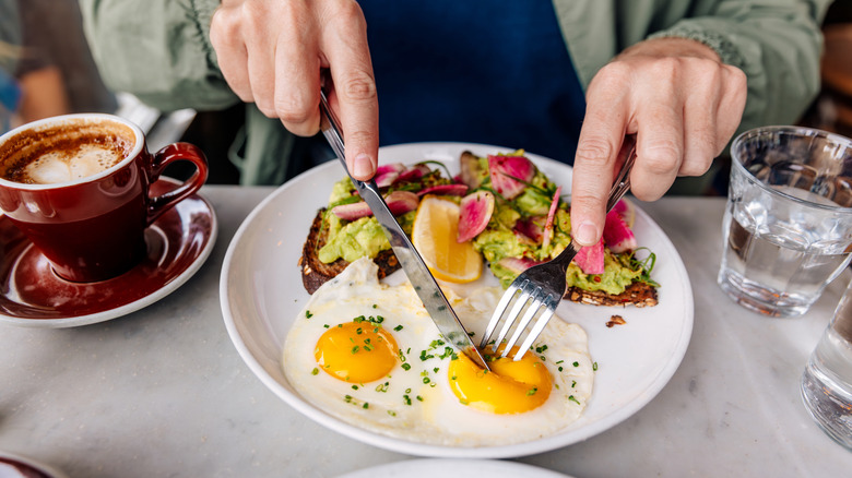 Cutting fried egg with fork and knife