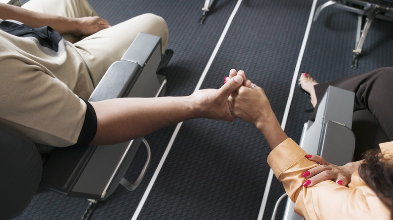 Couple holding hands in airplane