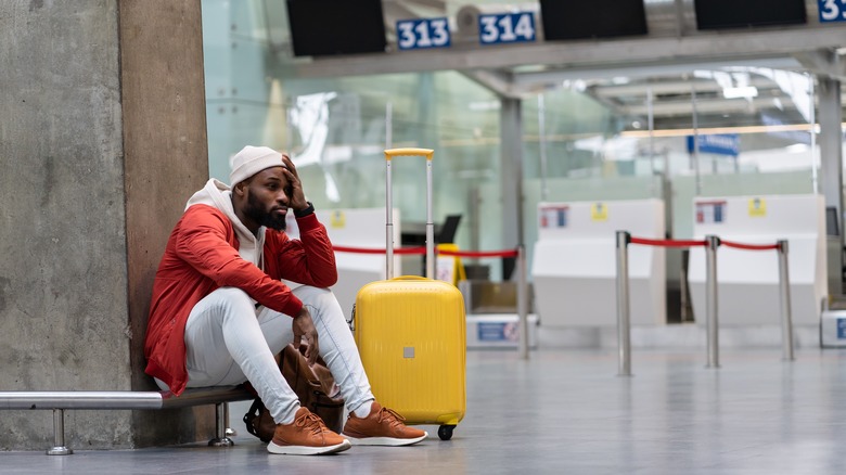 Tired man with luggage in airport