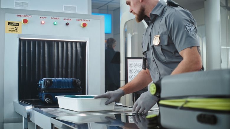 A TSA officer checks a security bin.