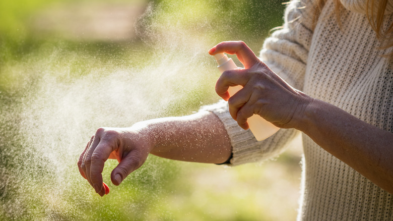 Woman spraying insect repellent
