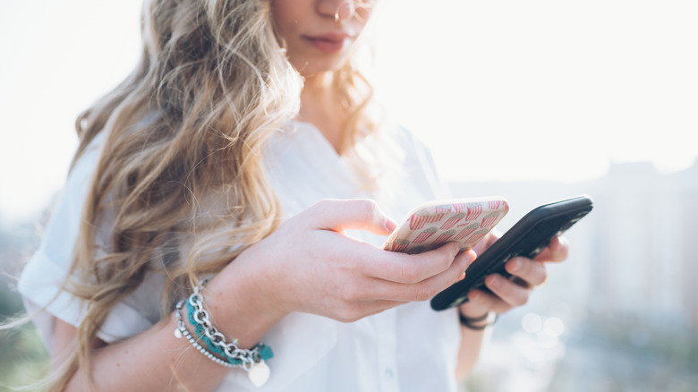 Woman consults two different smart phones