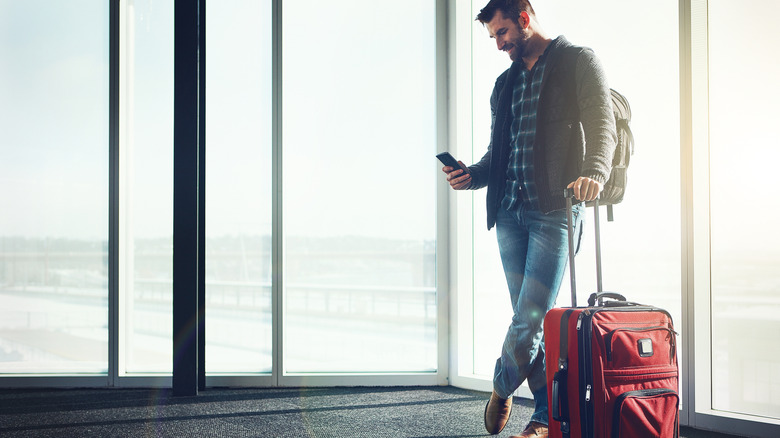 Man checks phone in airport terminal