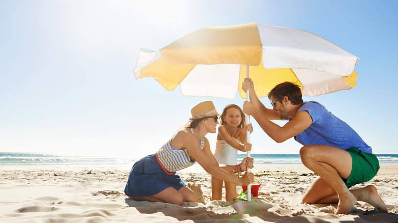 Family setting up beach umbrella