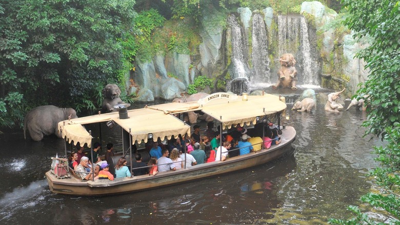 Disney's Jungle Cruise boat passes elephants under a waterfall.