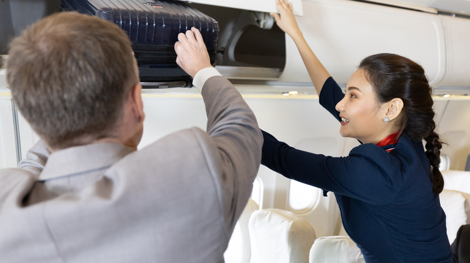 The Unexpected Reason Flight Attendants Will Never Help You Stow Your  Luggage