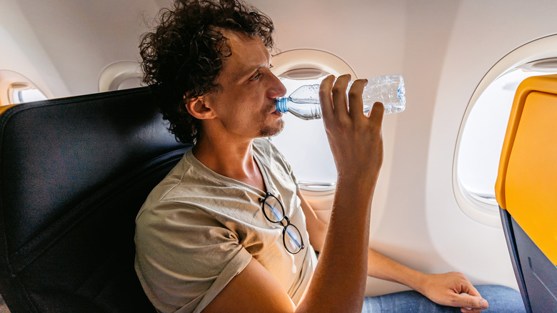 Plane traveler drinking from water bottle 