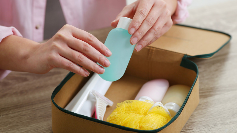 Person packing toiletries in bag