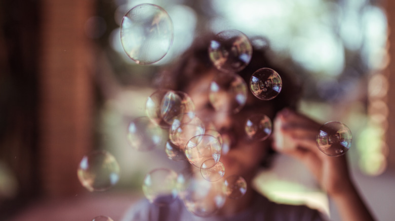 Young child blows bubbles