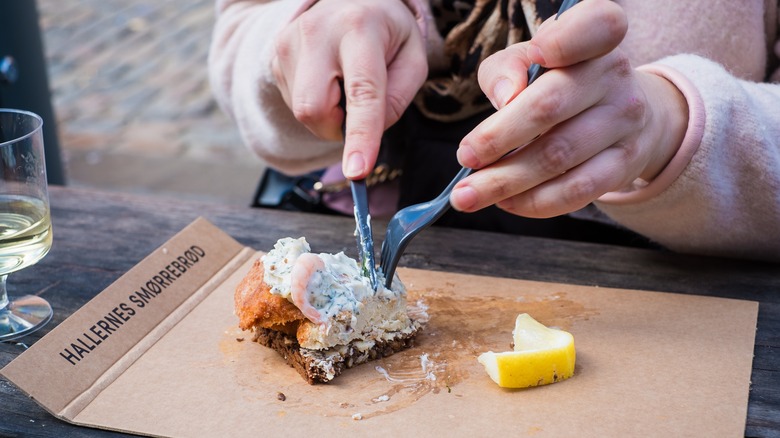 Person eating smørrebrød with silverware