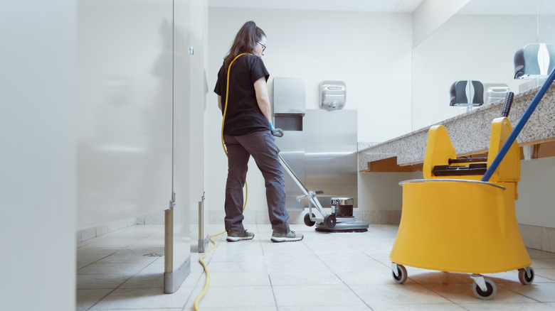 A woman cleans a public bathroom.