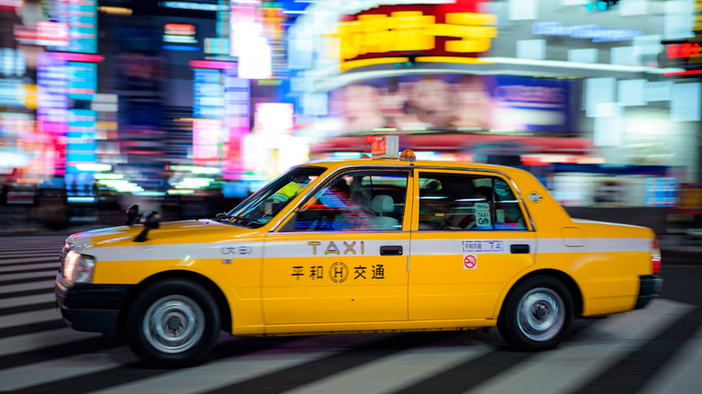 A taxi crusing down the neon-lit streets of a Japanese city