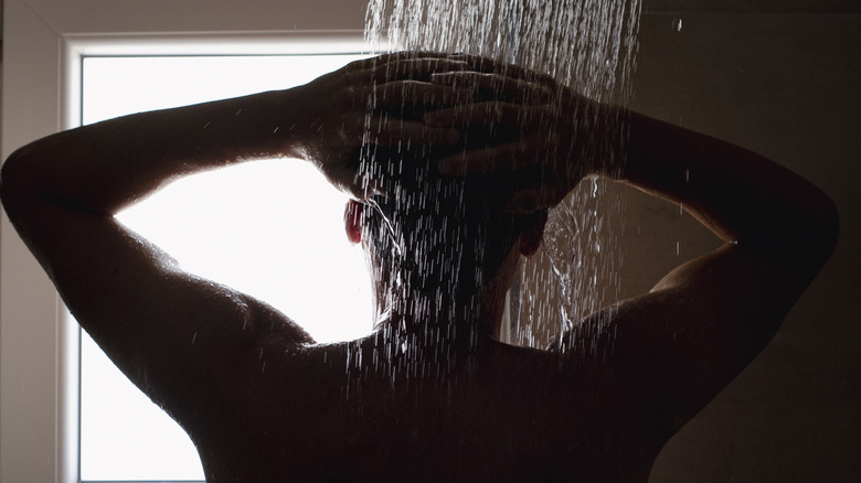 Close-up of a person showering, backlit.