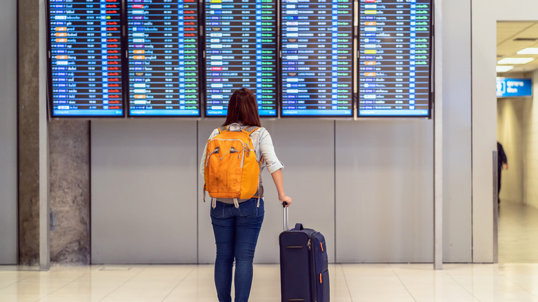 Traveler looking at airport departure screen