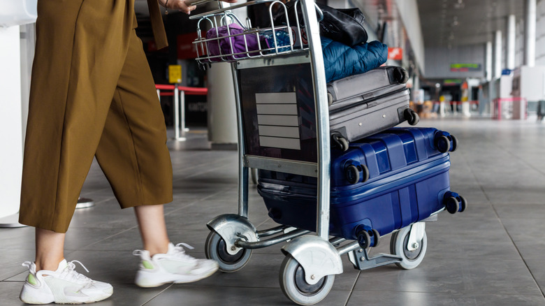 A woman pushing a baggage cart in an airport