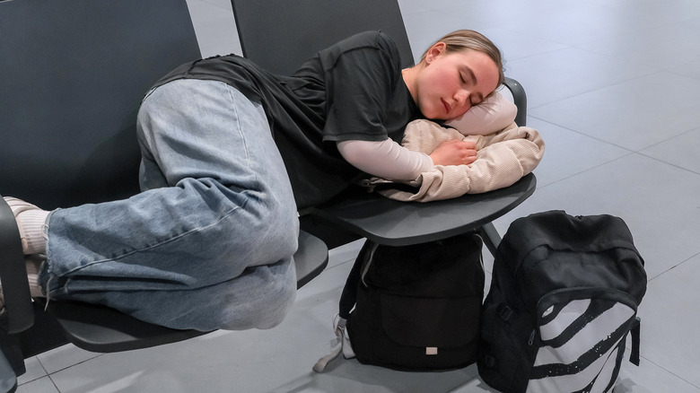 A woman curled up on an airport seat