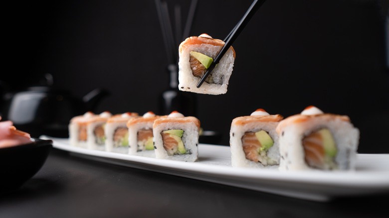 A diner lifts a piece of sushi with chopsticks