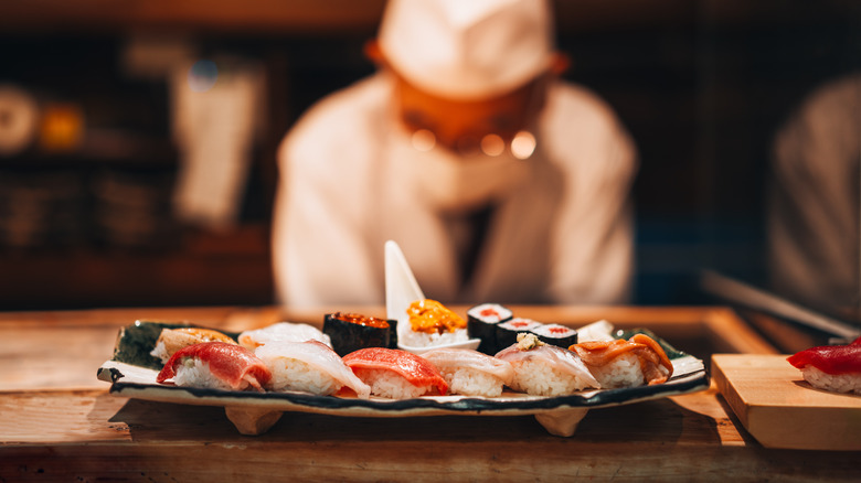 A chef examines a plate of nigiri sushi