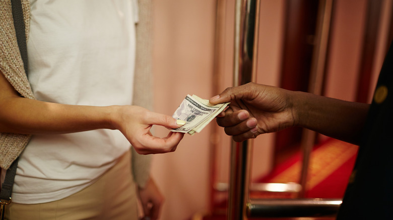 Hotel guest handing cash to bellhop