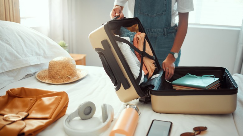 person with suitcase on bed