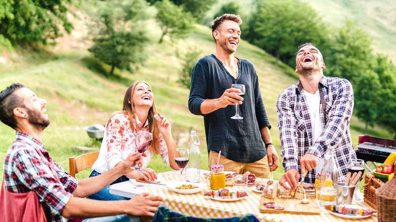 Friends laughing at an outdoor picnic 