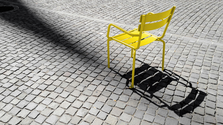 A yellow chair stands on cobblestone