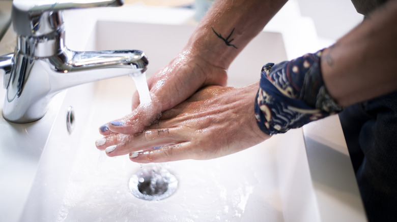 A person washes hands in a sink